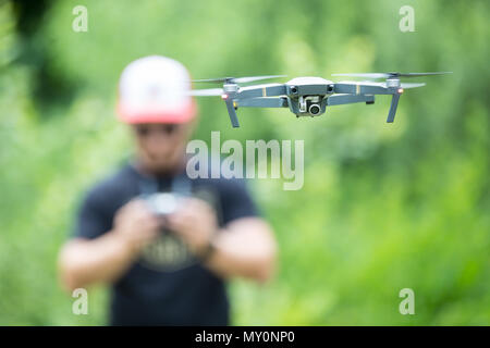 Junger Mann mit Fernbedienung und Fliegen mit drohne im Park. Stockfoto