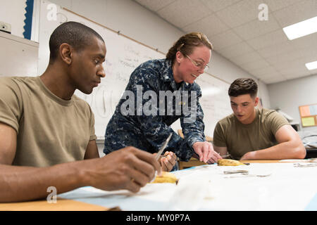 Cmrd. Cheryl Varner (Mitte), ein Arzt aus Expeditionary medizinische Einrichtung der Großen Seen in Great Lakes, Illinois, demonstriert die Vernähung während Armee Sgt. Yakini Moseley (links), eine Krankenschwester aus der 75th Combat Support Hospital (CSH) in Atlanta, GA, und SPC. Hunter Myers (rechts), ein Arzt aus dem 75. CSH in Tuscaloosa, AL, beobachten Sie am Alabama Wellness Innovative Readiness Training (IRT) Mission vom 29. Mai 2018 in Monroe County High School in Henderson, Ala das IRT gemeinsame Schulungsmaßnahmen für die Soldaten stellt, Flieger und Matrosen an der Mission teilnehmen. (US Air National Guard Fotos b Stockfoto