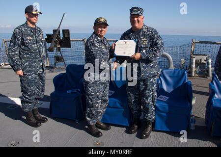 161105-N-N 0901-114 MITTELMEER (Nov 5, 2016) - Cmdr. Ken Pickard, kommandierender Offizier, USS Carney (DDG64), Mitte, wird die Meritorious Service Medal von Kapitän reichen Dromerhauser, Commodore, Destroyer Squadron 60 verliehen, die während eines Befehls Zeremonie an Bord der USS Carney (DDG64) Nov. 5, 2016. Carney, einem der Arleigh-Burke-Klasse geführte-missile Destroyer, Vorwärts - Rota, Spanien bereitgestellt werden, ist die Durchführung einer Routinepatrouille in den USA 6 Flotte Bereich der Maßnahmen zur Unterstützung der US-amerikanischen nationalen Sicherheitsinteressen in Europa. (U.S. Marine Foto von Petty Officer 2. Klasse Ramiro Flores/Freigegeben) Stockfoto