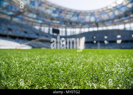 Grass on stadium in sunlight. Closeup of a green football field. Wet stadium grass in the morning light during watering irrigation. Close up macro of soccer or football field. green grass field background. Empty stadium. Stockfoto