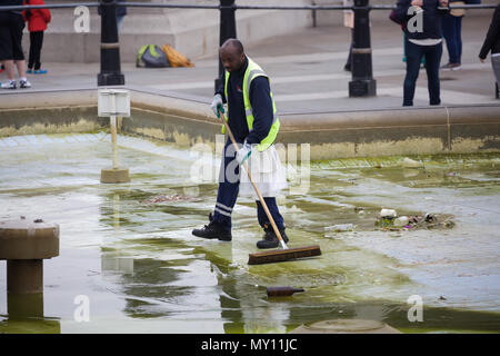 London, UK, 5. Juni 2018, ein Mann fegt und putzt die leere Brunnen am Trafalgar Square auf einer langweiligen, grauen und kalten typischer Tag Sommer, die Prognose für die Verbesserung und wärmeres Wetter als die Woche geht weiter. Credit: Keith Larby/Alamy leben Nachrichten Stockfoto