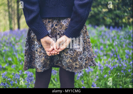 Eine junge Frau steht auf einer Wiese mit ihren Händen hinter dem Rücken Stockfoto