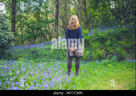 Eine junge Frau steht auf einer Wiese mit ihren Händen hinter dem Rücken Stockfoto