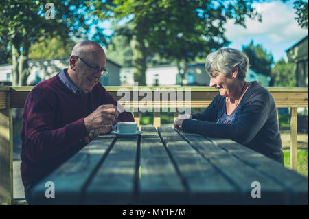 Ein älteres Paar sitzen an einem Tisch in einem Caravan Park und trinken Kaffee Stockfoto