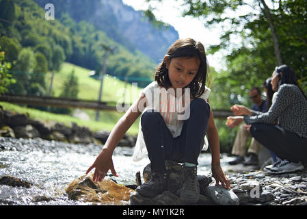 Zwei nette junge Mädchen spielen zusammen entlang eines Baches hoch oben in den Schweizer Bergen während einer Sommer Urlaub in der Sonne Stockfoto