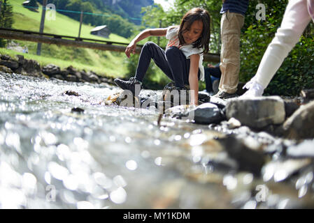 Zwei nette junge Mädchen spielen zusammen entlang eines Baches hoch oben in den Schweizer Bergen während einer Sommer Urlaub in der Sonne Stockfoto