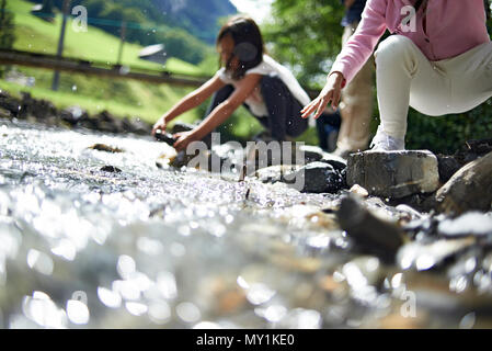 Zwei nette junge Mädchen spielen zusammen entlang eines Baches hoch oben in den Schweizer Bergen während einer Sommer Urlaub in der Sonne Stockfoto