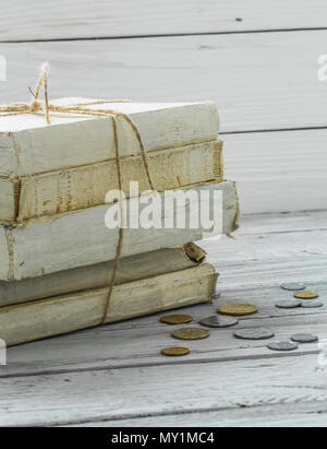 Alte weiße Bücher mit Geld Bill und Münzen auf weißem Holz- Hintergrund Stockfoto
