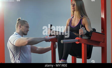 Personal Trainer sein Klient Korrektur während des Trainings in der Turnhalle Stockfoto