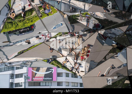 Der Eingang aus Glas in ein Einkaufszentrum in Harajuku, Tokio, spiegelt Menschen vorbei in die Straße vor dem Gebäude. Stockfoto