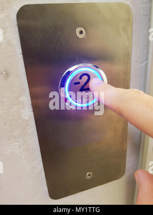 Finger zu drückt die Taste zum Hintergrund, Aufzug in einem Gebäude durch Drücken der Taste Stockfoto