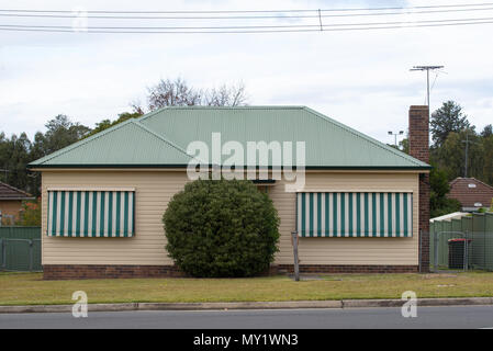 Eine einfache und wirtschaftlich gebaut, L-förmiges Holz- und weatherboard plattierter Stahl überdachte Home mit einem gemauerten Schornstein eventuell in den 50er oder 60er Jahren erbaut Stockfoto