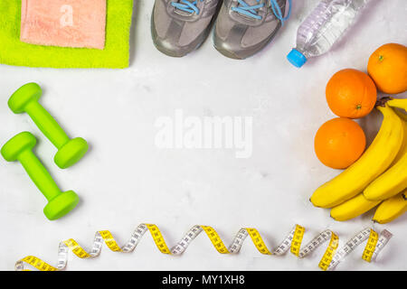 Das Konzept einer gesunden Lebensweise und Sport, vor dem Hintergrund der Laufschuhe, Hanteln und Handtücher, Bananen und Orangen, Stockfoto