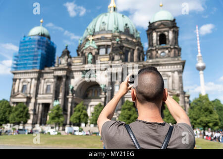 Nahaufnahme eines jungen kaukasischen Mann, von hinten gesehen, ein Bild von der Berliner Dom, in Berlin, Deutschland, mit seinem Smartphone Stockfoto