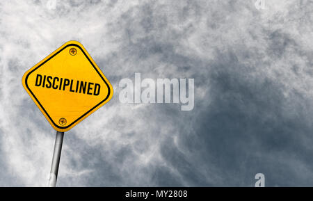 Diszipliniert - gelbes Schild mit bewölktem Himmel Stockfoto