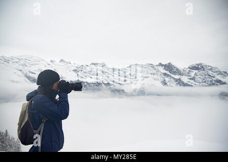 Asiatische Frau im Winter Kleidung stehen auf einem Berg über dem Nebel im Tal, einige Fotos können Sie über Ihr Mobiltelefon Stockfoto