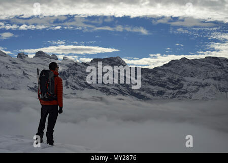 Bergsteiger Bergsteiger auf dem Gipfel der Welt genießen Sie die herrliche Aussicht auf die Berge, wie er über dem Nebel im Tal steht unten Stockfoto