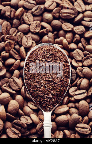 Gemahlener Kaffee in einem Löffel auf gerösteten Kaffeebohnen Hintergrund. Ansicht von oben. Konzept der Kaffee mahlen Stockfoto