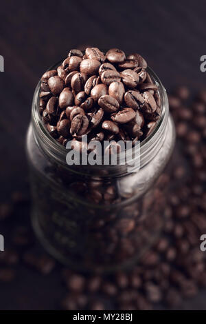 Kaffeebohnen Auslaufen aus einem jar auf einer hölzernen Tabelle counter. Top Retro Vintage anzeigen Stockfoto