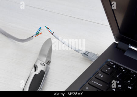 Kabel Internet auf einen Laptop, den Schnitt durch ein Taschenmesser verbunden. Konzept der Internet verbot, cencorship und Unterbrechung. Stockfoto