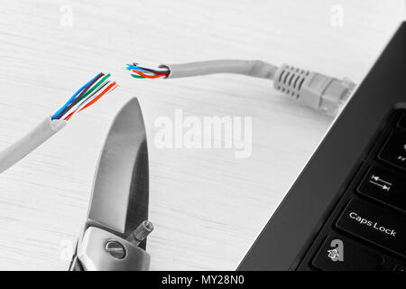 Internet verbot, cencorship und Unterbrechung. Kabel Internet mit einem Laptop Schnitt durch ein Taschenmesser verbunden. Stockfoto