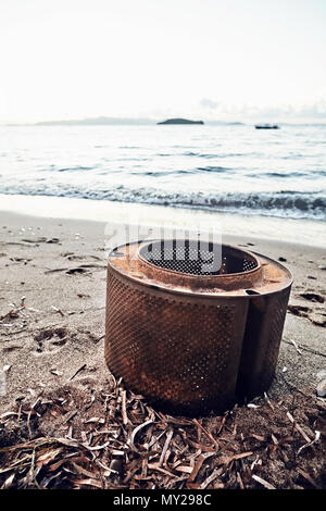 Rostige Waschmaschine Whirlpool am Strand, die die Verschmutzung der Umwelt durch industrielle Abfälle Stockfoto