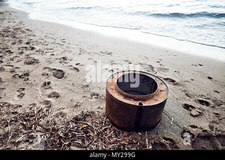 Rostige Waschmaschine Whirlpool am Strand, die die Verschmutzung der Umwelt durch industrielle Abfälle Stockfoto