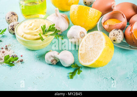 Hausgemachte mayonnaise Sauce mit Zutaten - Zitrone, Eier, Olivenöl, Gewürze und Kräuter, hellblauer Hintergrund Kopie Raum Stockfoto