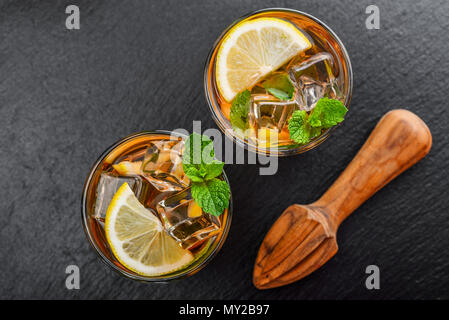 Zwei Gläser Eistee süsse Limonade mit Zitrone und Minze auf schwarzem Schiefer Hintergrund, Ansicht von oben Stockfoto