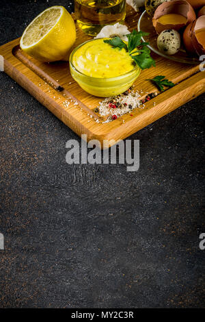 Hausgemachte mayonnaise Sauce mit Zutaten - Zitrone, Eier, Olivenöl, Gewürze und Kräuter, schwarz konkreten Hintergrund Kopie Raum Stockfoto