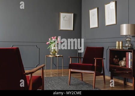 Die eleganten Psychologe Büro Interieur mit zwei roten Sesseln vor jeder anderen zwischen einem goldenen Tisch mit Blumen und Vintage, Holzgehäuse. Real Stockfoto