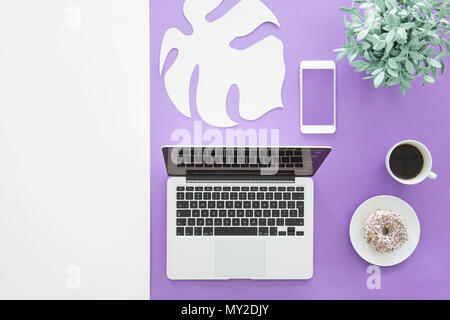 Blick von oben auf die Laptop und Mockup von Smartphones auf Violett Schreibtisch mit Tasse Kaffee und Donut Stockfoto