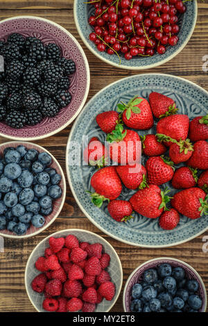 Verschiedene frische Sommer Beeren in Schalen auf hölzernen Hintergrund closeup Stockfoto