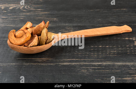 Scheiben getrocknete Äpfel in einem Löffel auf hölzernen Hintergrund Stockfoto