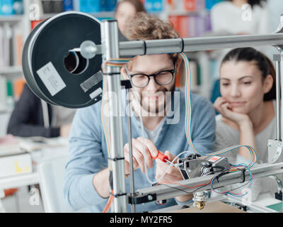 Studenten der Ingenieurwissenschaften mit einem 3D-Drucker im Labor, ein Student wird mit einem Schraubendreher Stockfoto