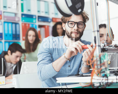 Studenten der Ingenieurwissenschaften mit einem 3D-Drucker im Labor, ein Student wird mit einem Schraubendreher Stockfoto