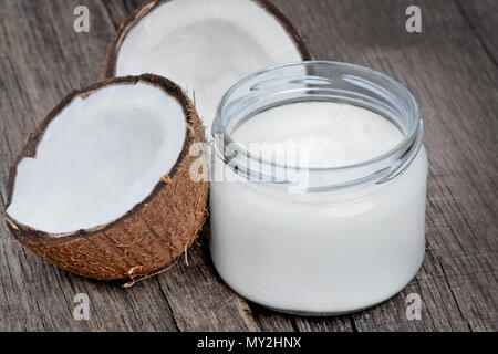 In der Nähe von frischem Kokosnussöl in Glaswaren auf alten Holztisch Stockfoto