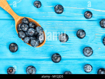 Löffel gefüllt mit Blaubeeren und Beeren auf Tisch verstreut Stockfoto