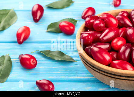 Teil der Schüssel mit cornel Beeren und Blätter auf dem Tisch verstreut Stockfoto