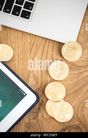 Bitcoins auf einen hölzernen Tisch neben einem Tablet-PC und Laptop Stockfoto
