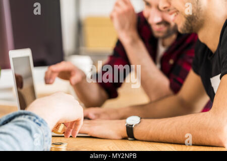 Gruppe der glücklichen Freunde zusammen in einem Laptop. Konzentrieren Sie sich auf die Hände des Menschen Holding cryptocurrency. Stockfoto