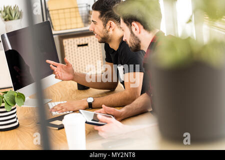 In der Nähe unscharf einer Anlage mit Kollegen lächelnd und sitzt vor einem Computer im Hintergrund Stockfoto