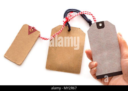 Nahaufnahme der Hand alte braune Papier Tag oder Etikett, Karton Preis auf weißem Hintergrund. Stockfoto