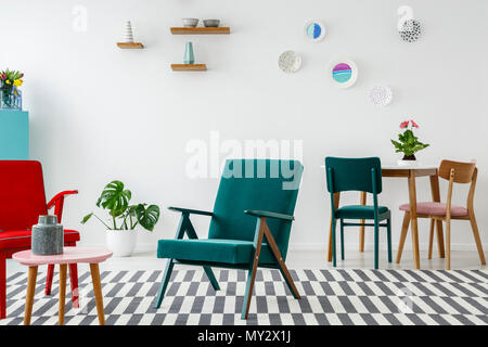 Grüne und rote Sessel auf gemusterten Teppich in bunten Flachbild Interieur mit Pflanzen und Platten Stockfoto