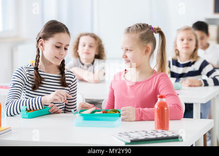 Mädchen reden über gesundes Essen mit Freund während der frühstückspause in der Schule Stockfoto