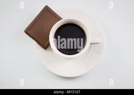Blick von oben auf eine weiße Kaffeetassen mit cookie Schokolade auf weißem Hintergrund, schwarzer Kaffee mit Cookie auf Weiß, Ansicht von oben. Stockfoto