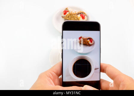 Mit einem Smartphone ein Foto Kaffee und süßes Cookie in weißen Hintergrund, Fotografie mit Smartphone Foto geschossen Kaffee und Süßes cookie Konzept. Stockfoto