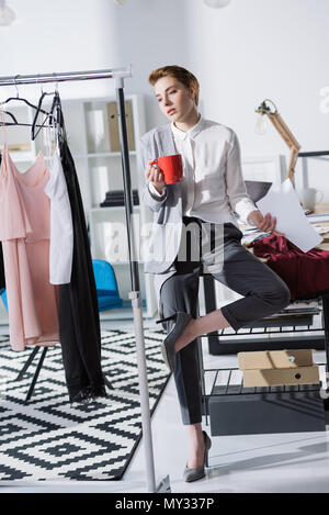 Junge stilvolle Mode Designer sitzen am Schreibtisch im Büro und Kleider Stockfoto