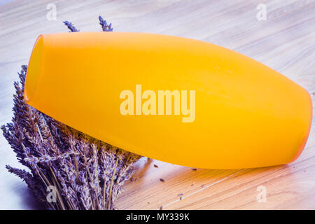 Trockenen Blumenstrauß aus Lavendelblüten mit orange Vase auf Holz Tisch Hintergrund, getrocknetem Lavendel Bündel. Stockfoto