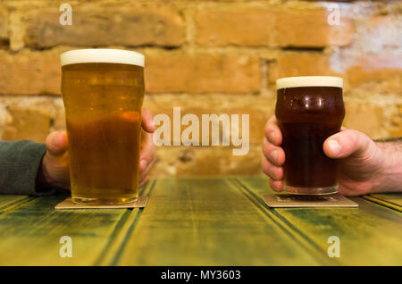 Freunde an der Bar Tisch halten zwei Pints Bier, Prost Stockfoto